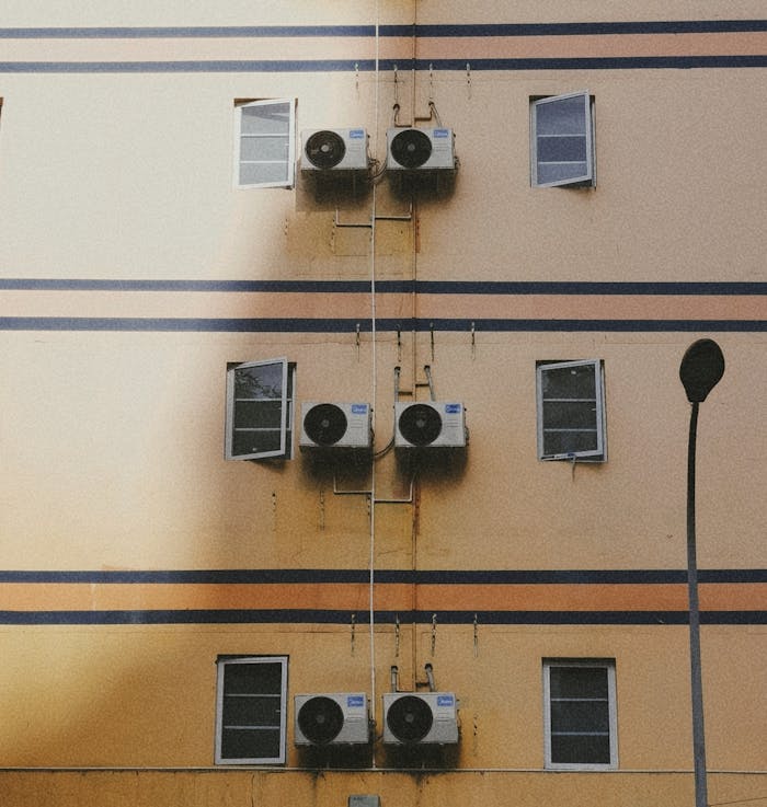 Yellow building exterior with air conditioners and windows, featuring a street lamp.
